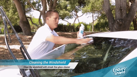Spraying and wiping EnduroShield rain repellent onto a car windshield