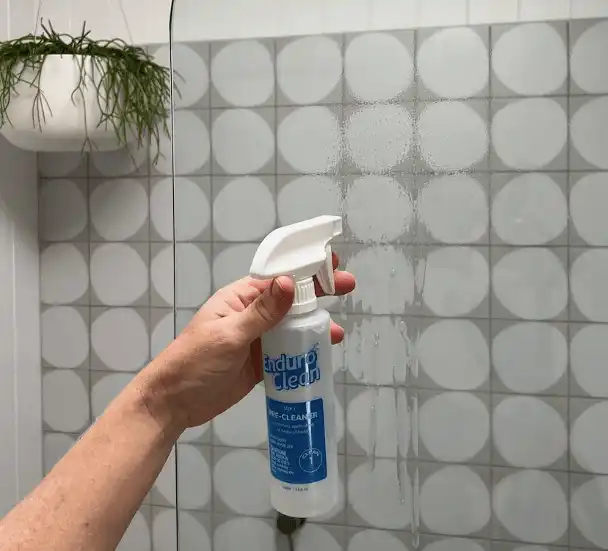 Customer in mask applying EnduroShield to bathroom glass