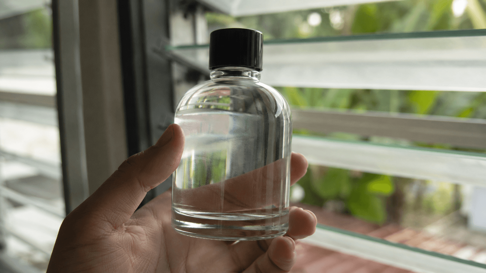 Macro close-up of a clear glass coating bottle showing the transparent liquid inside — nothing opaque, nothing toxic-looking