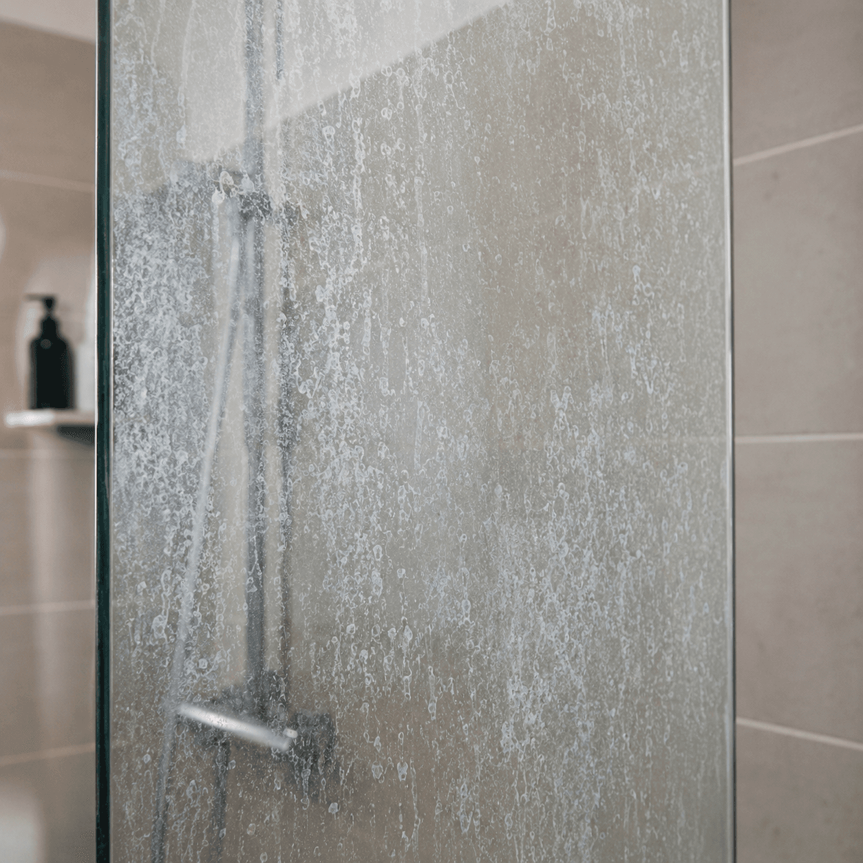 Shower glass at month twenty-four — cloudy etching across the panel